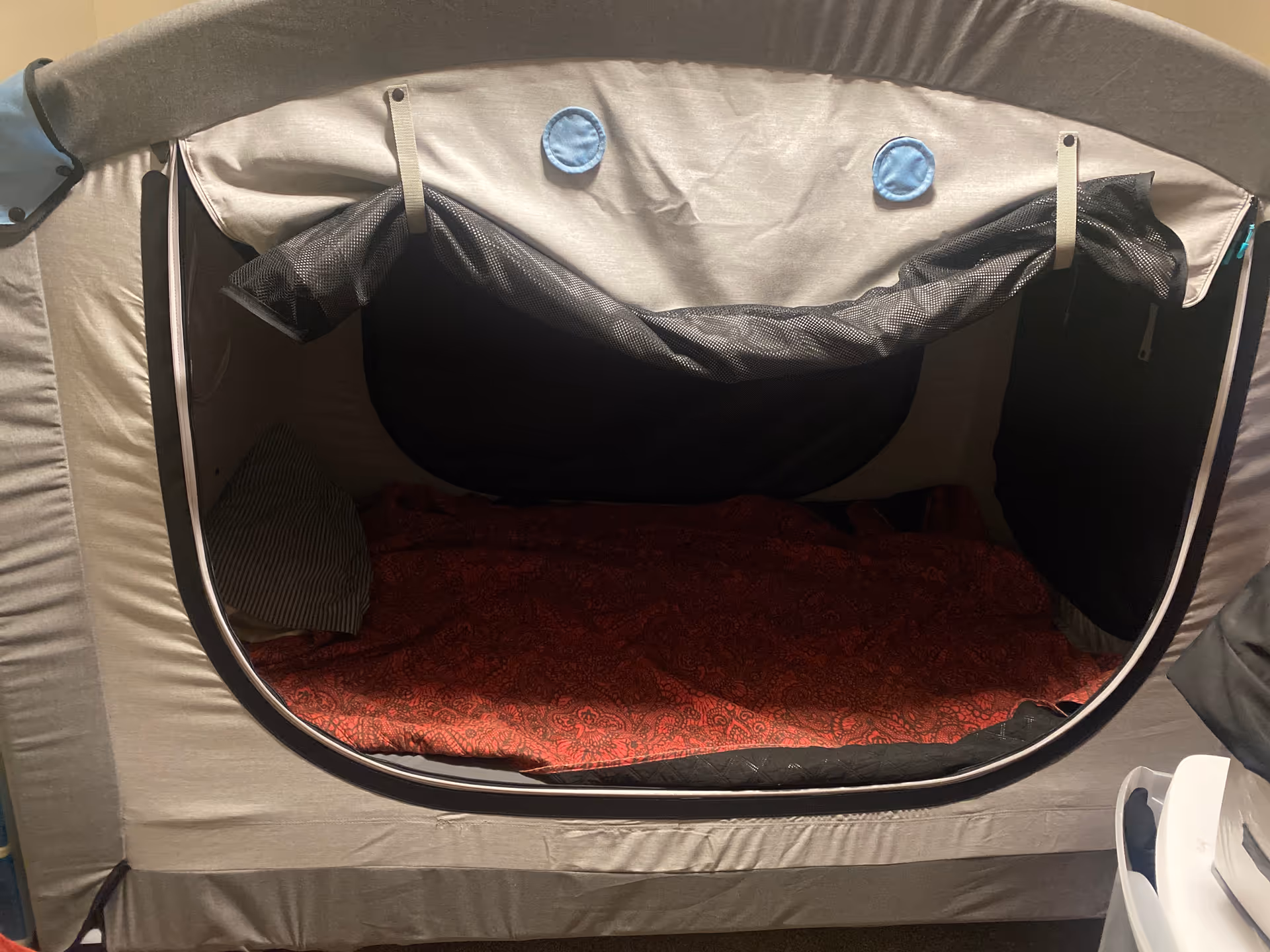 Compact privacy sleeping pod with red blanket inside an interior room.