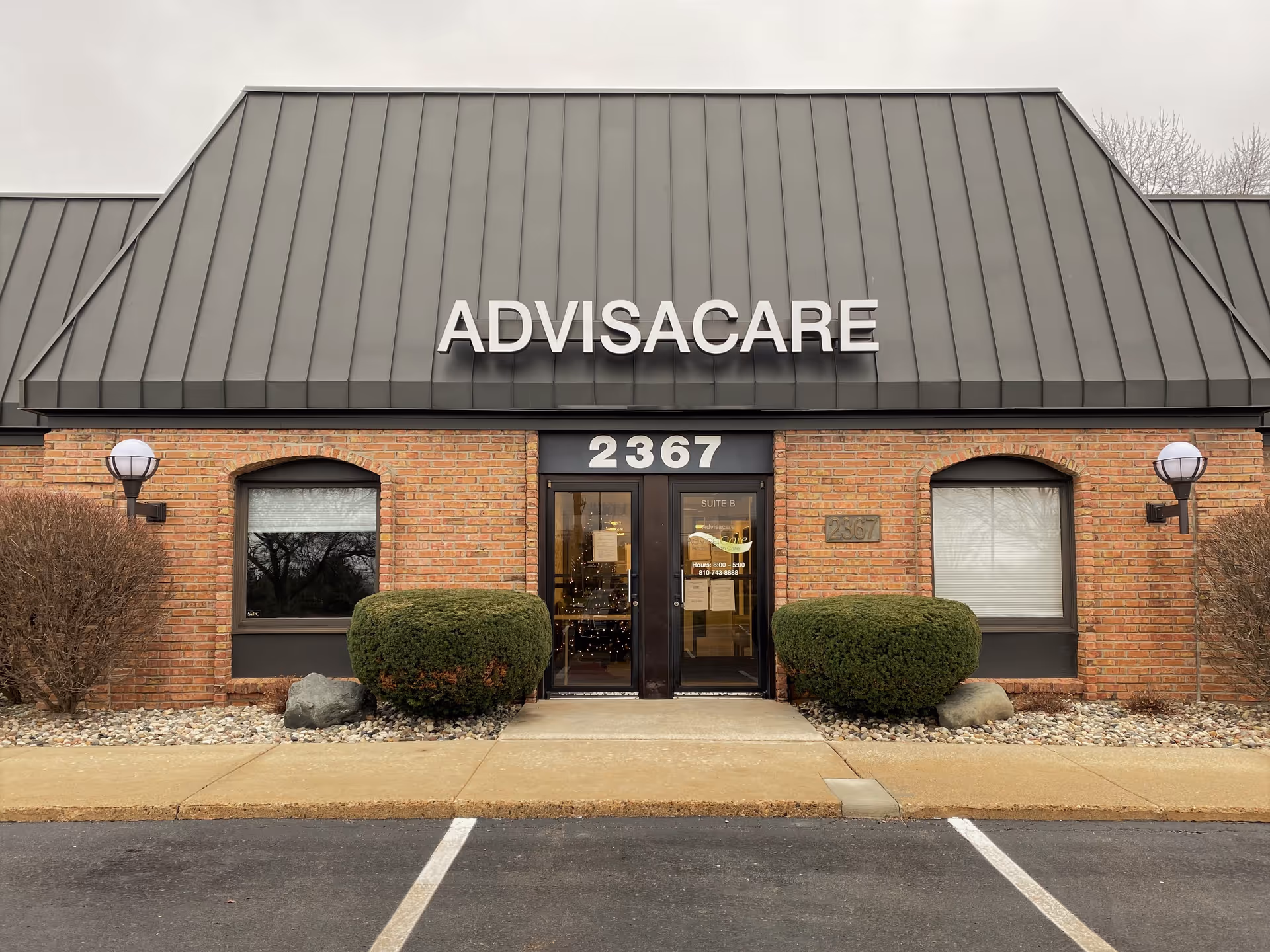 The facade of ADVISACARE building features brick walls and a dark metal roof.