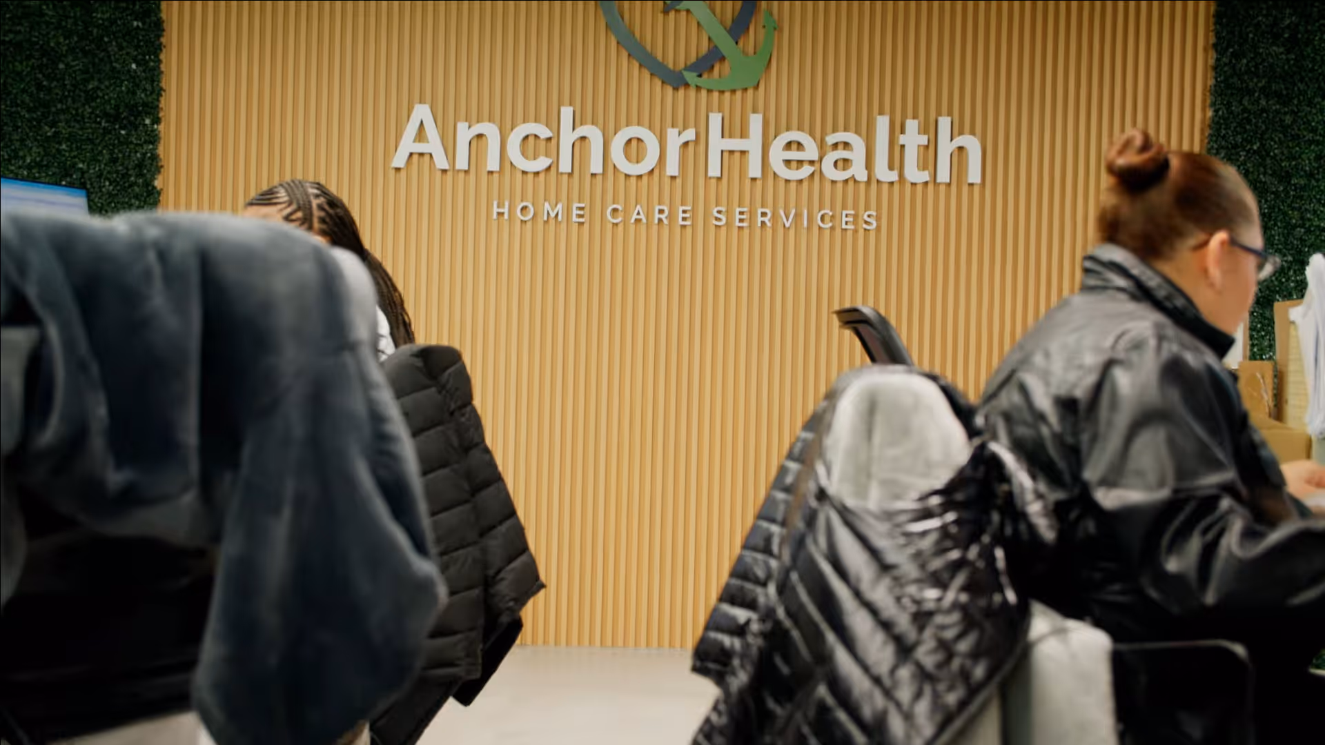 Reception area with Anchor Health sign on wood wall and visitors.
