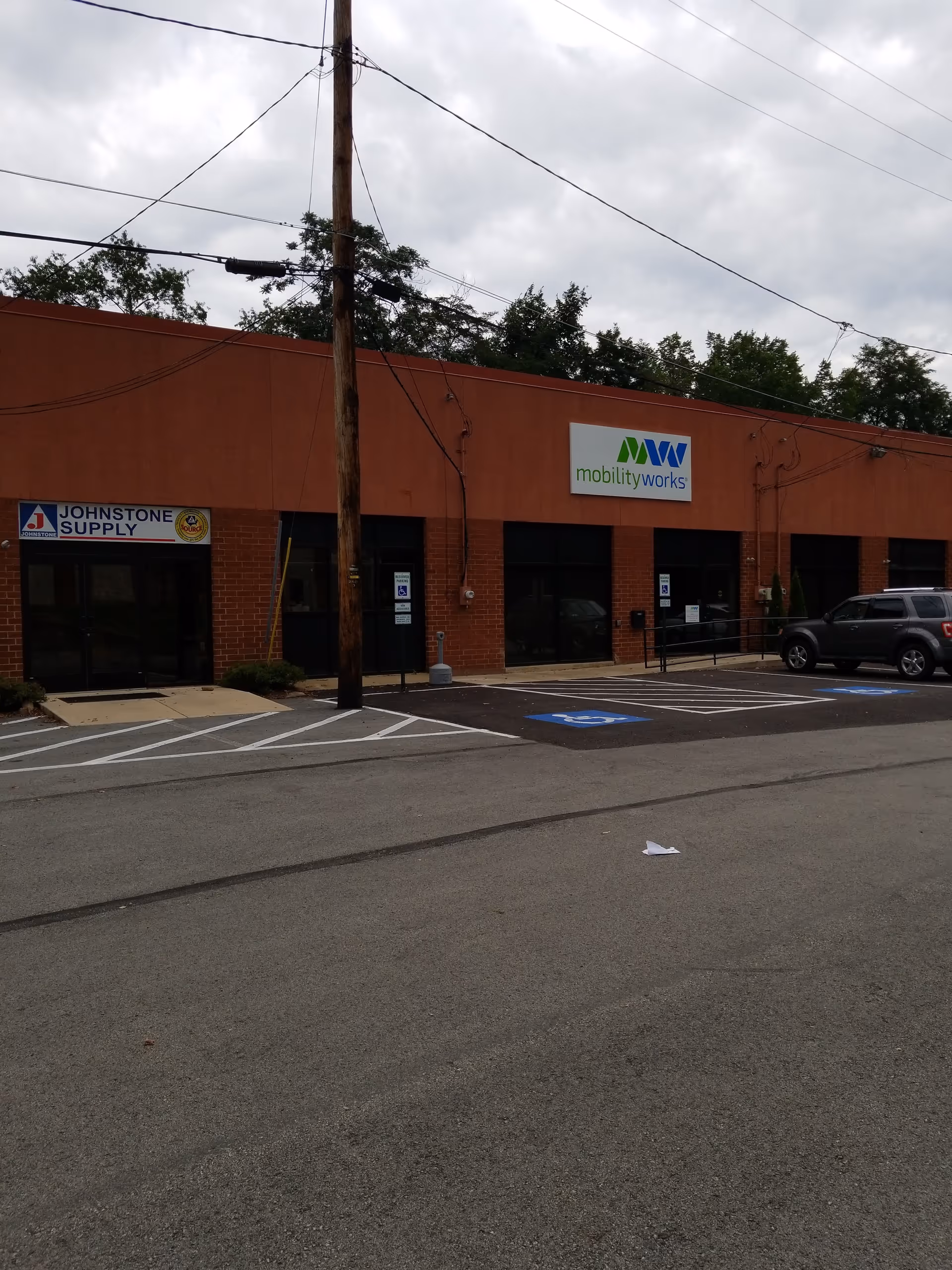 Exterior view of MobilityWorks facility with signage and parked cars in front.