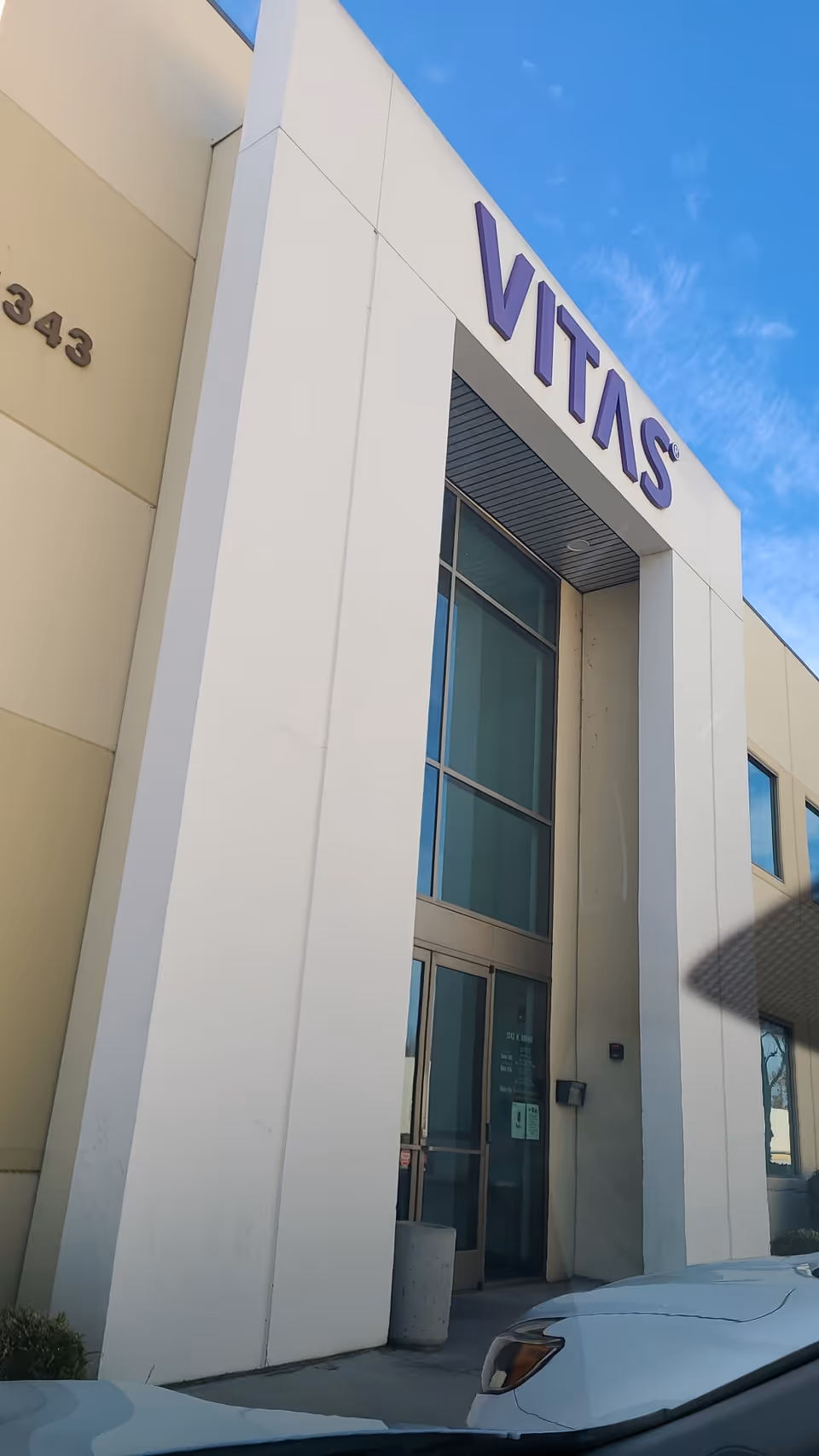 VITAS Healthcare building entrance with white columns, glass doors, and blue sky.