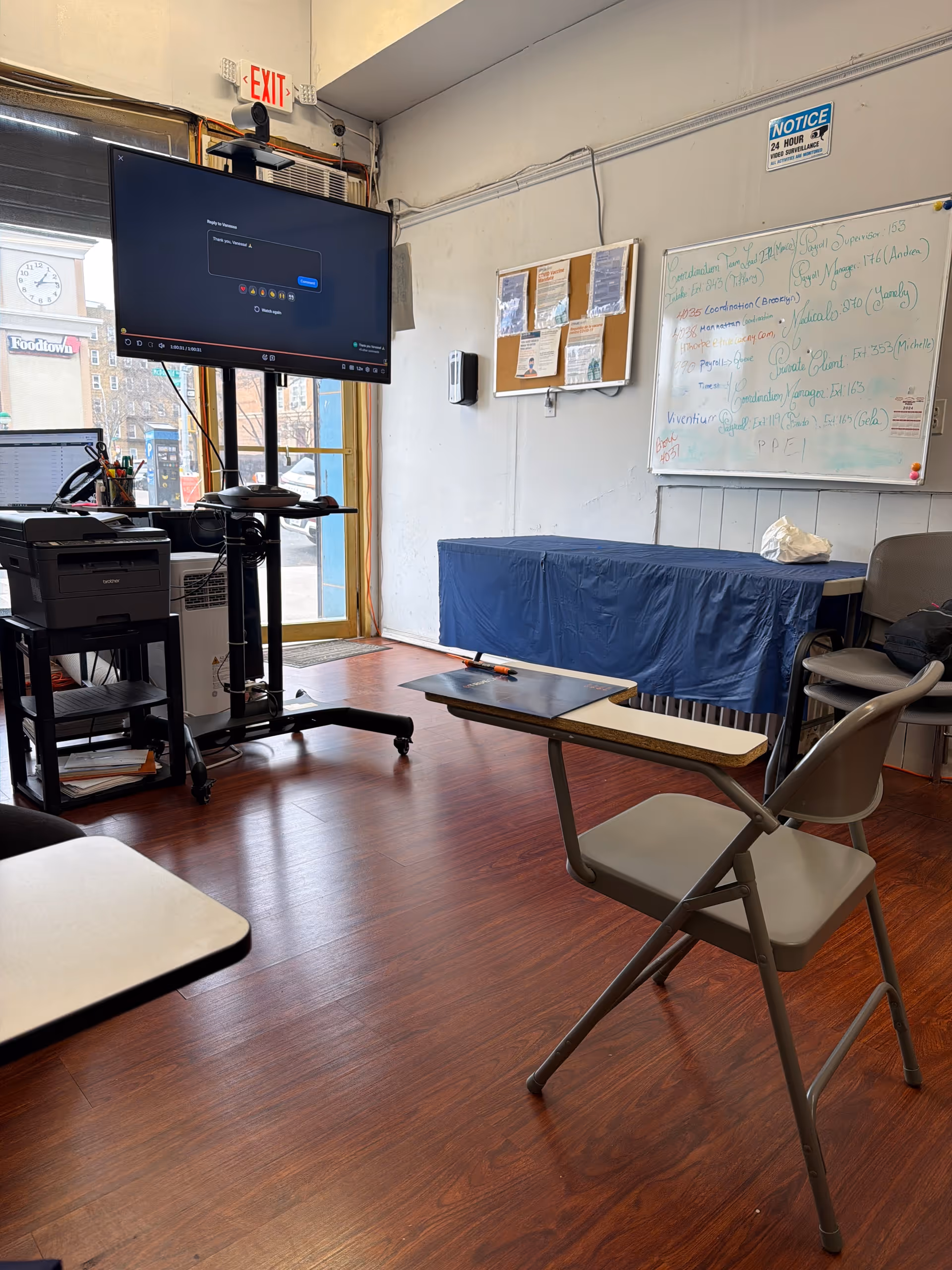 Classroom-style training room with a large monitor on a stand, whiteboard, and folding chairs.