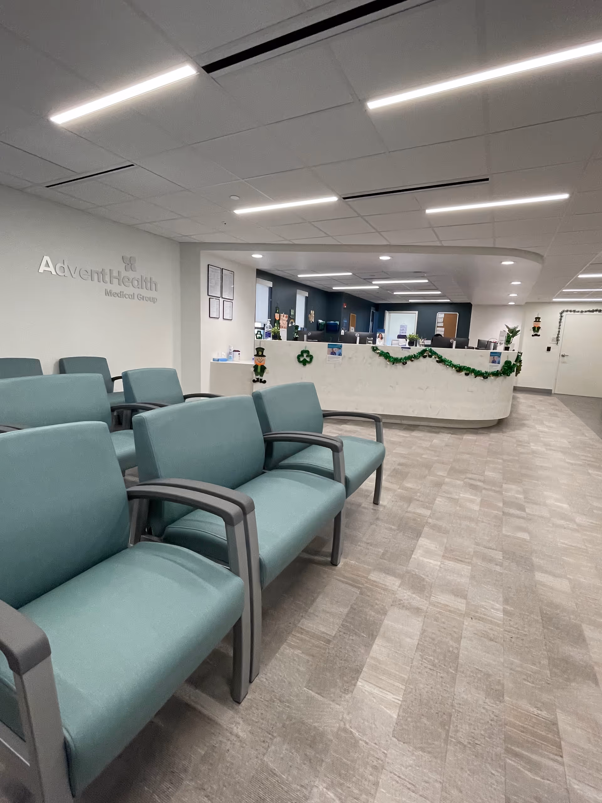 Waiting area with teal chairs, a curved reception desk, and holiday garland.