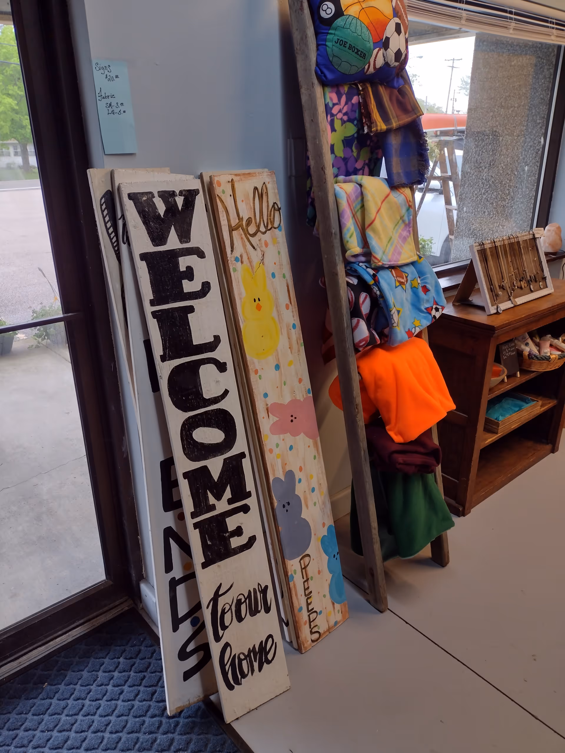 Colorful welcome signs and blankets lean beside a doorway in a cozy facility lobby.