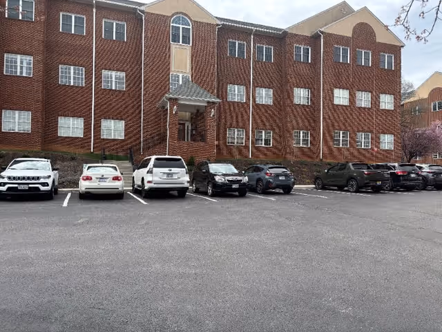 Brick multi-story facility with a central entrance and front parking lot.