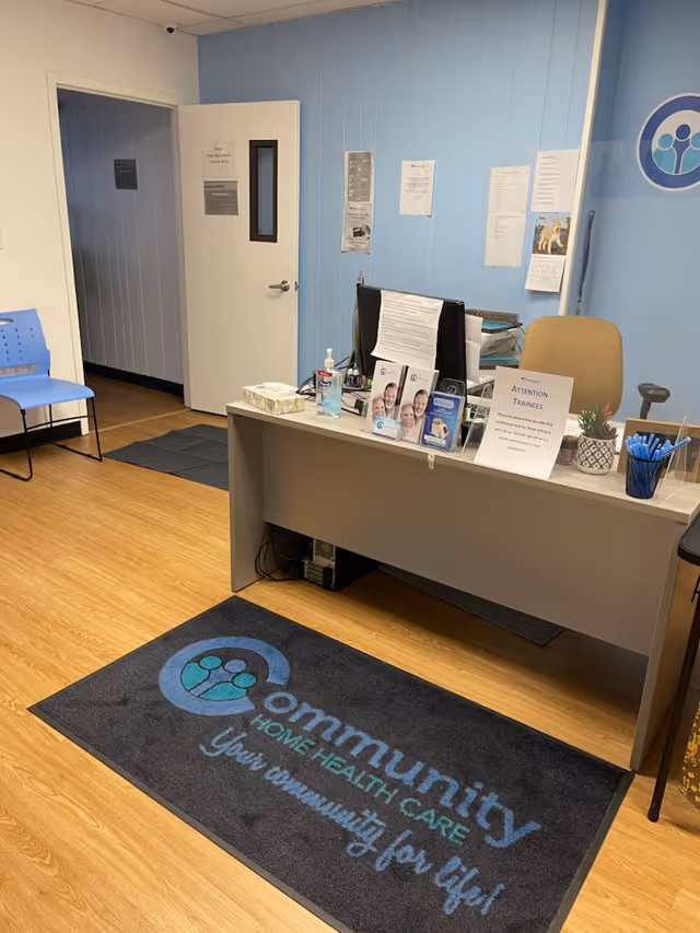 Reception desk in blue-walled office with computer, brochures, and hand sanitizer.