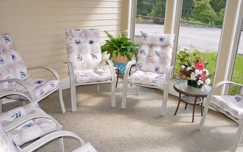 Sunlit indoor seating area with floral cushioned chairs arranged in a circle.