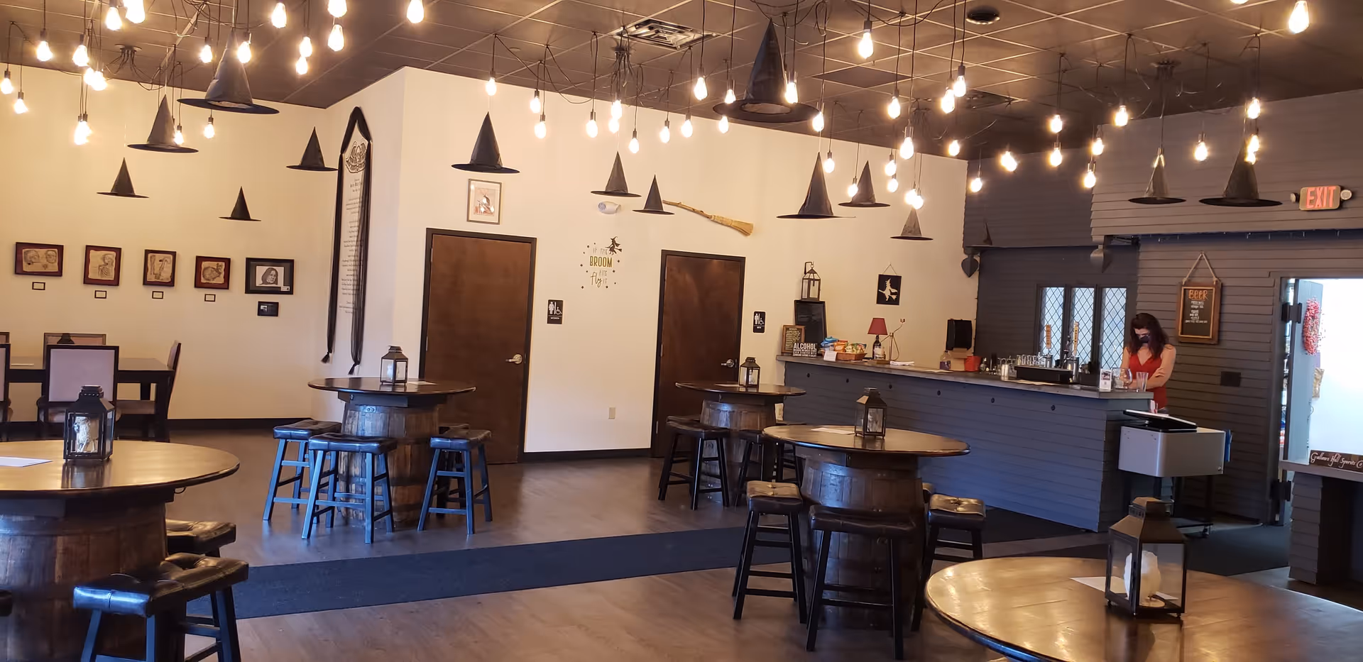 Communal dining area with round tables, stools, and a staff member at a counter.