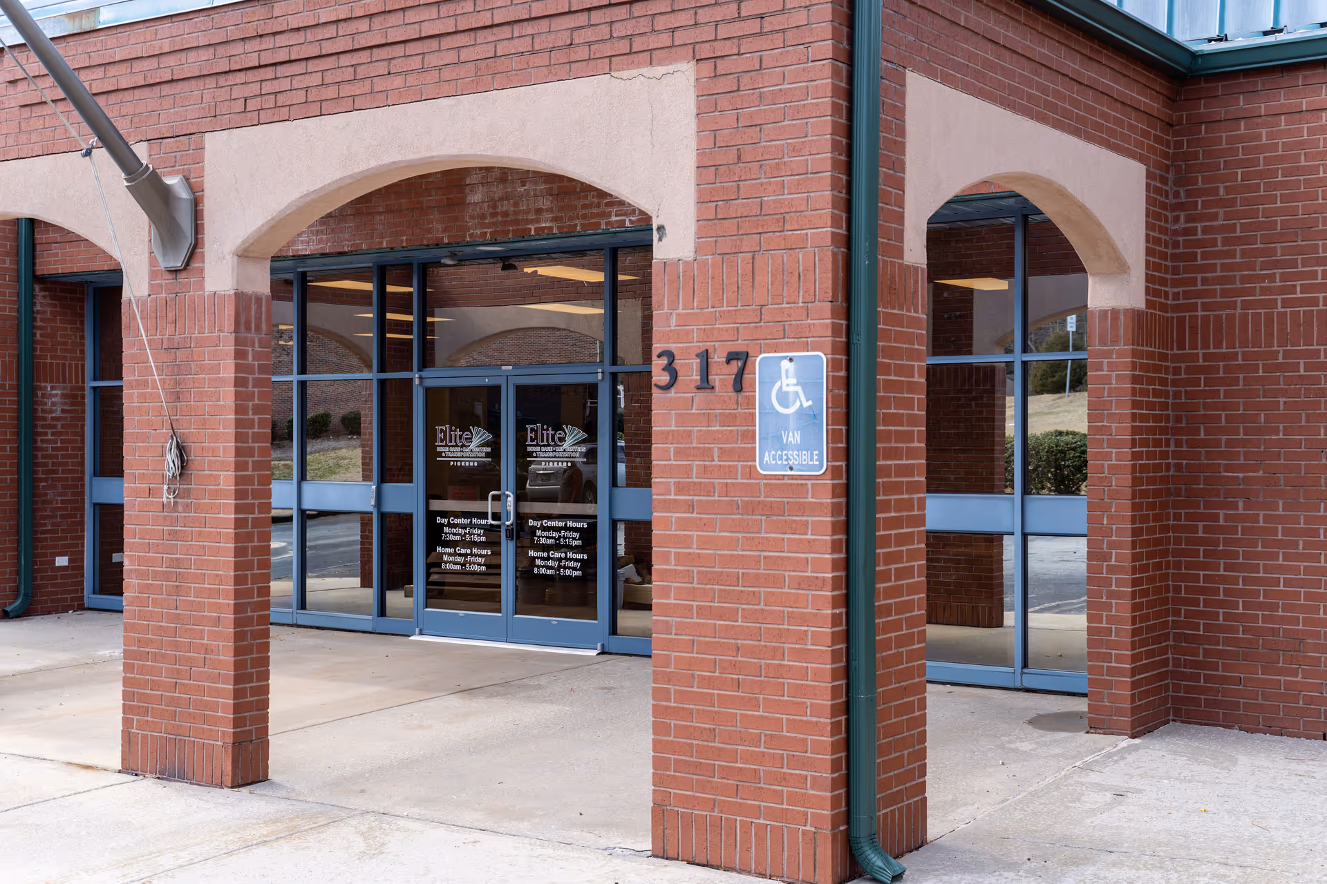 Brick facility entrance for Elite Home Care and Day Centers, with glass doors and wheelchair sign.