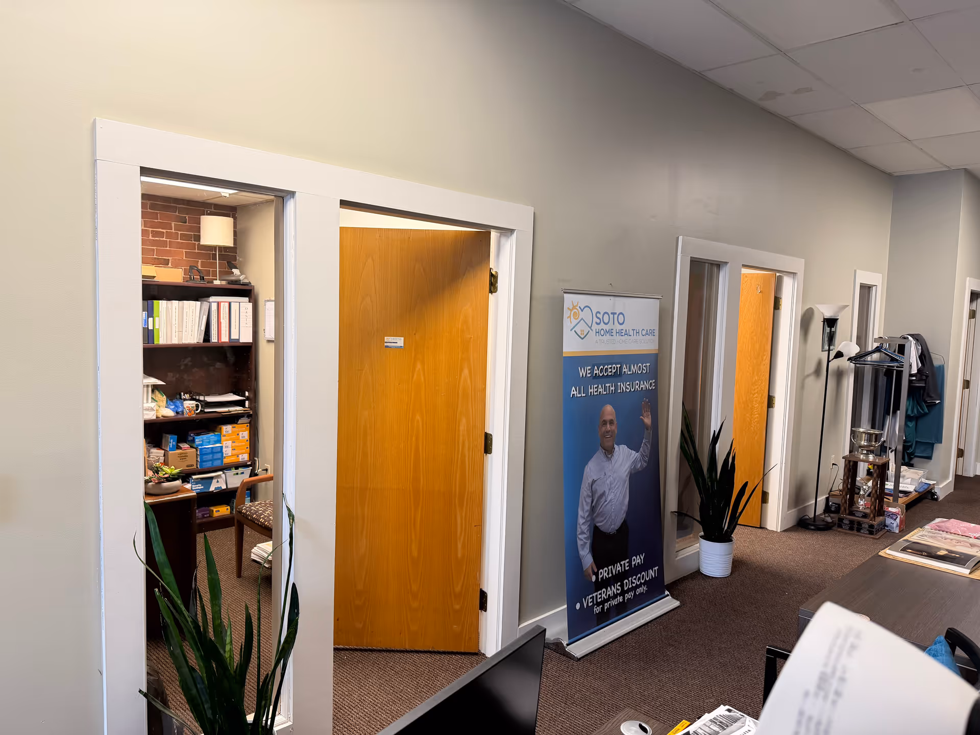 Interior hallway with open storage room, wood door, and a standing Soto banner.