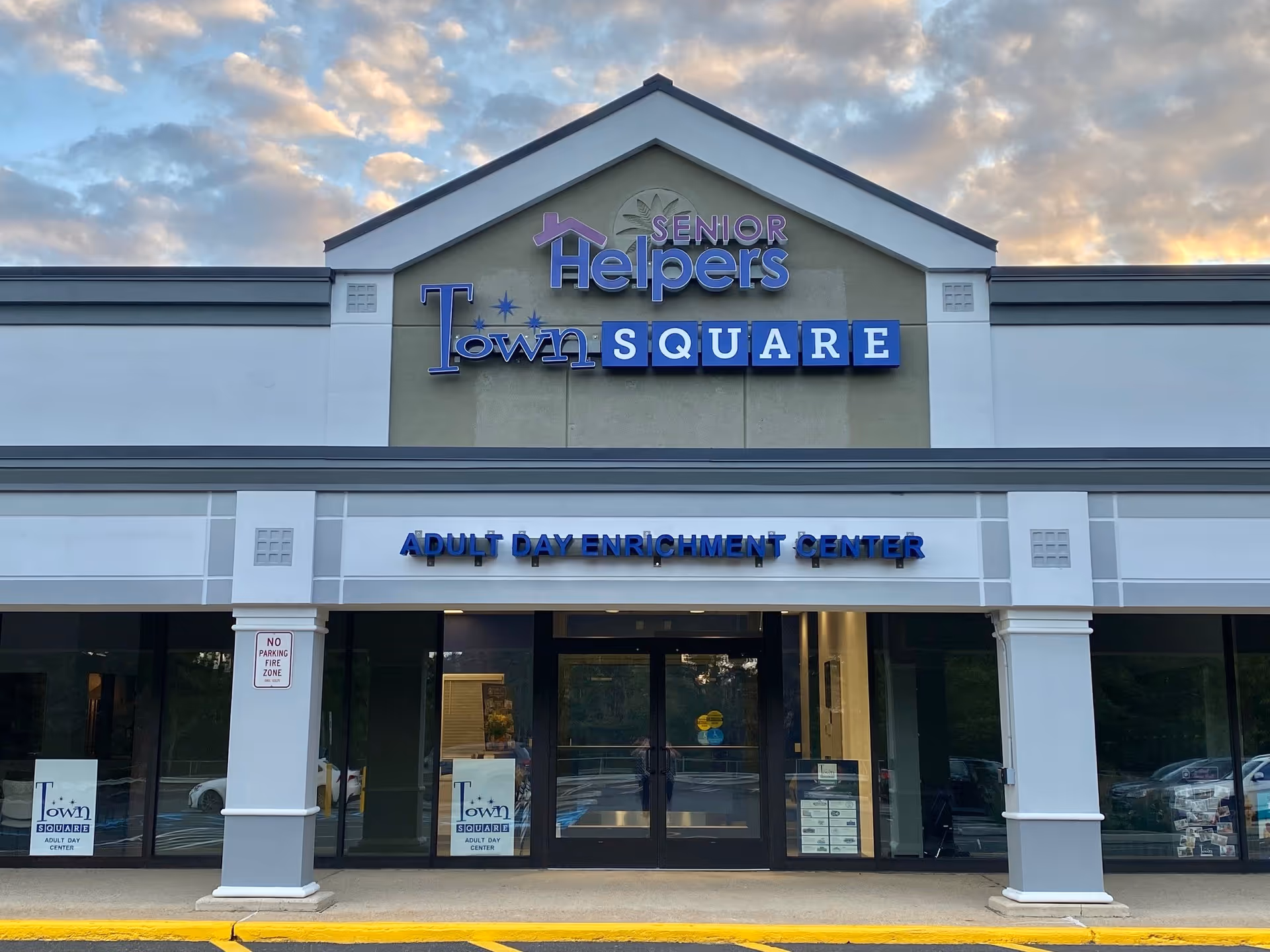 Exterior view of a Senior Helpers building front with blue signage and glass doors.