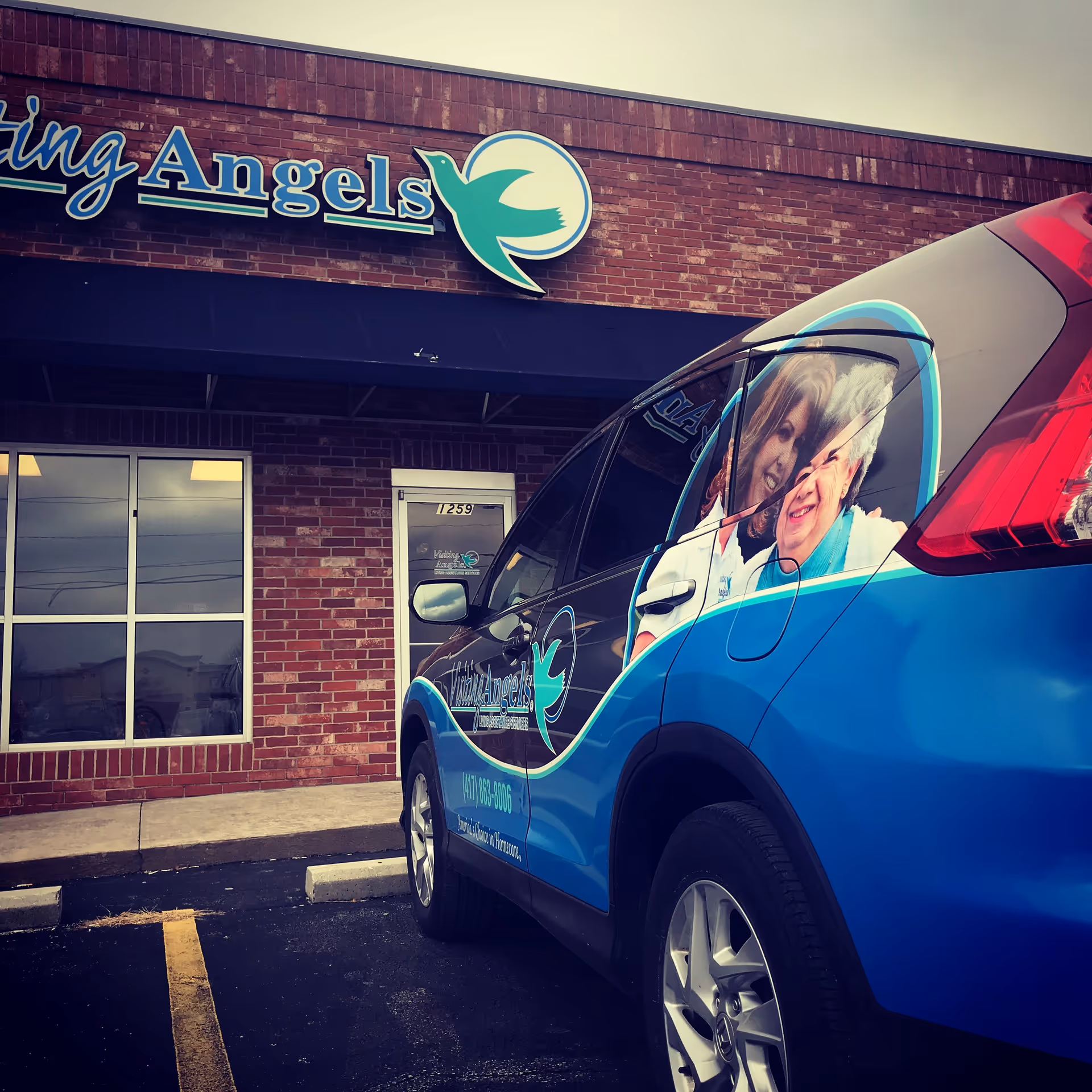 Exterior view of Visiting Angels building with a blue branded care van parked in front.