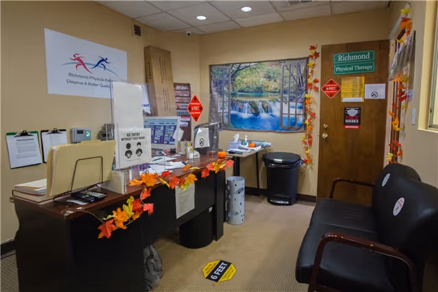 Reception desk at Richmond Physical Therapy clinic with autumn leaves and waterfall poster.