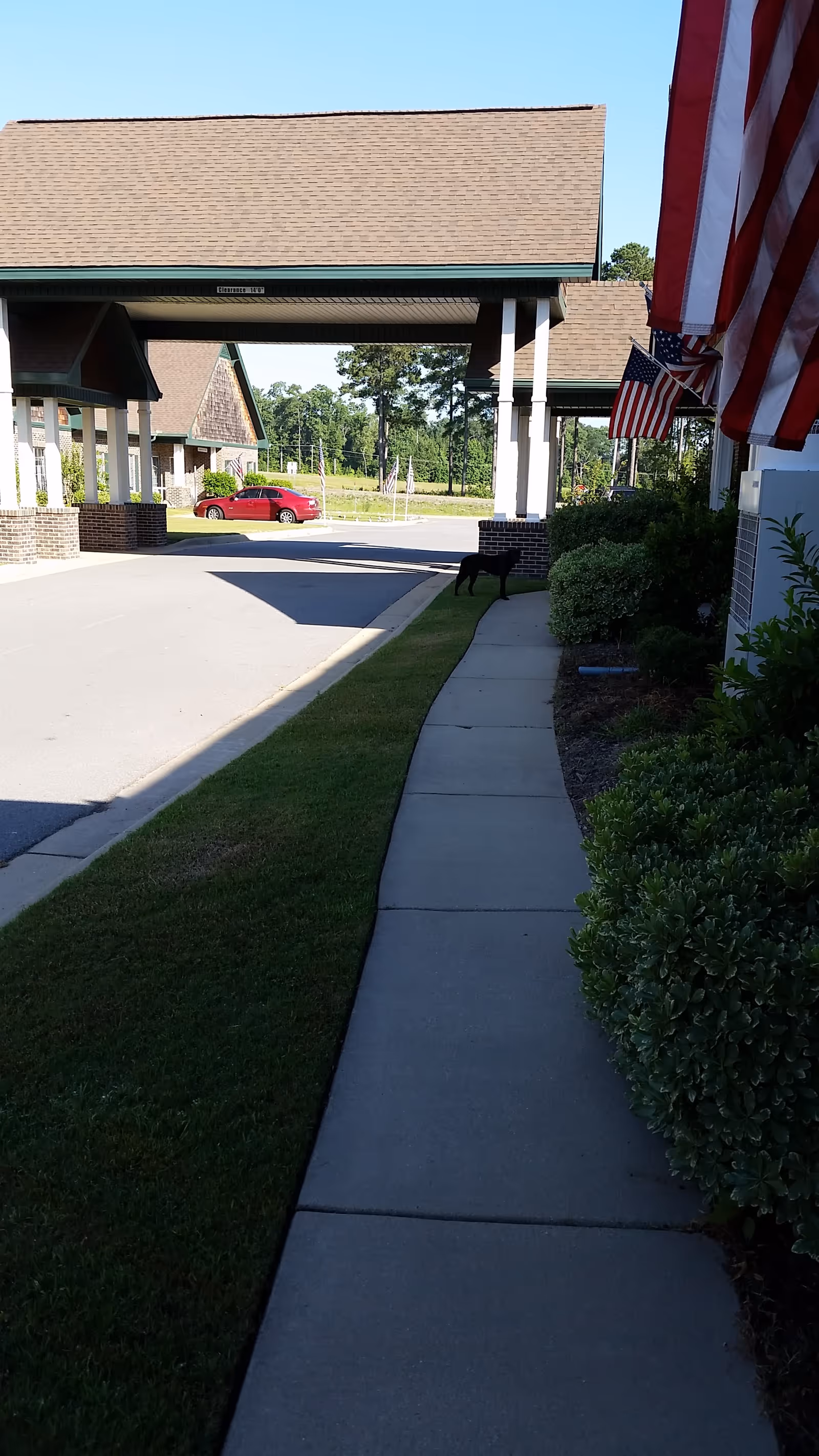 Exterior view of Life Touch Hospice entrance with canopies, flags, and a sidewalk.