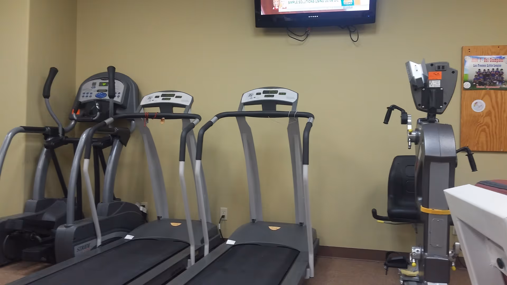 Fitness room with treadmills, a stationary bike, and a wall-mounted TV.