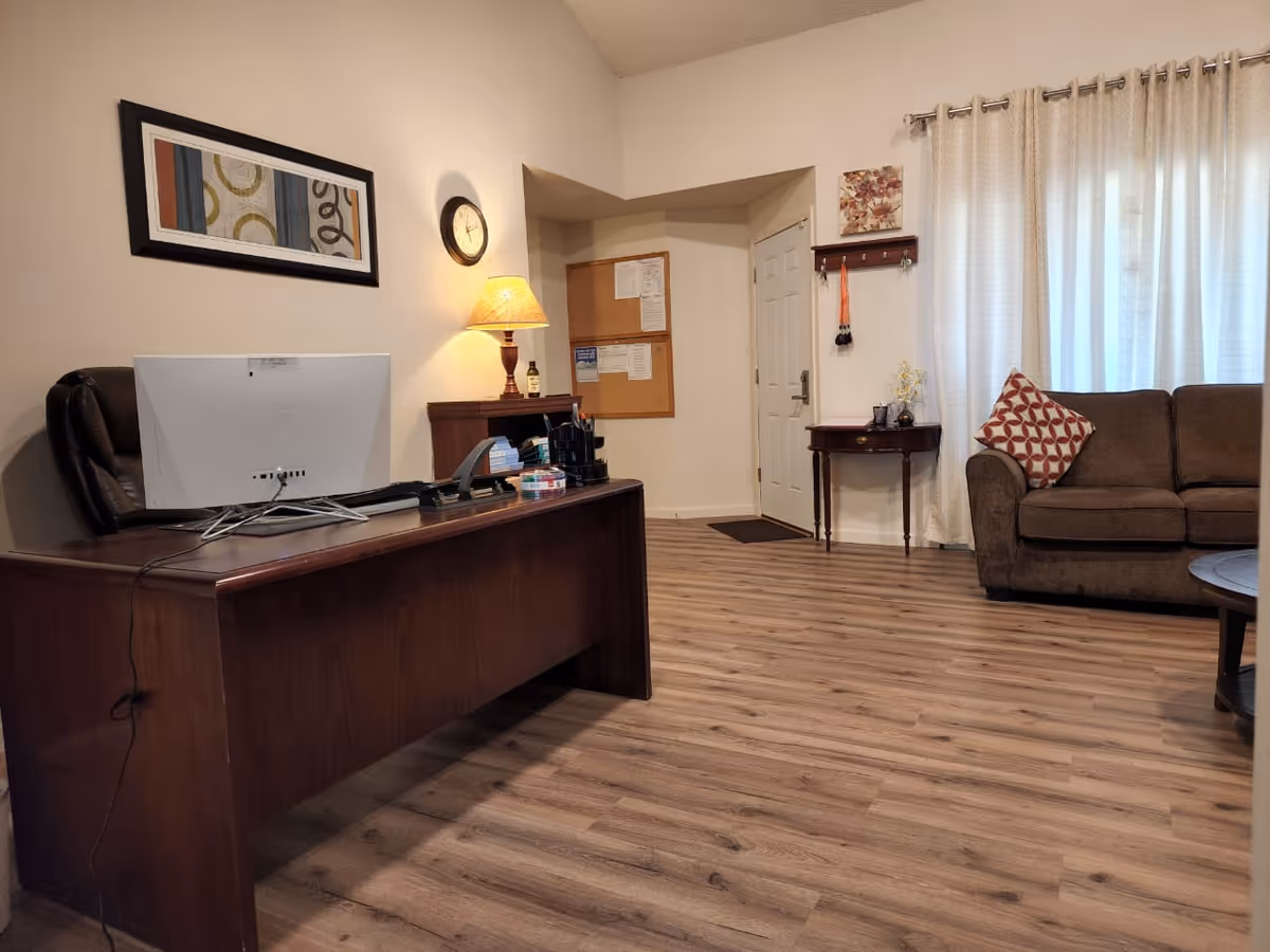 Reception desk and seating area in a senior living lobby with bulletin board and curtains.