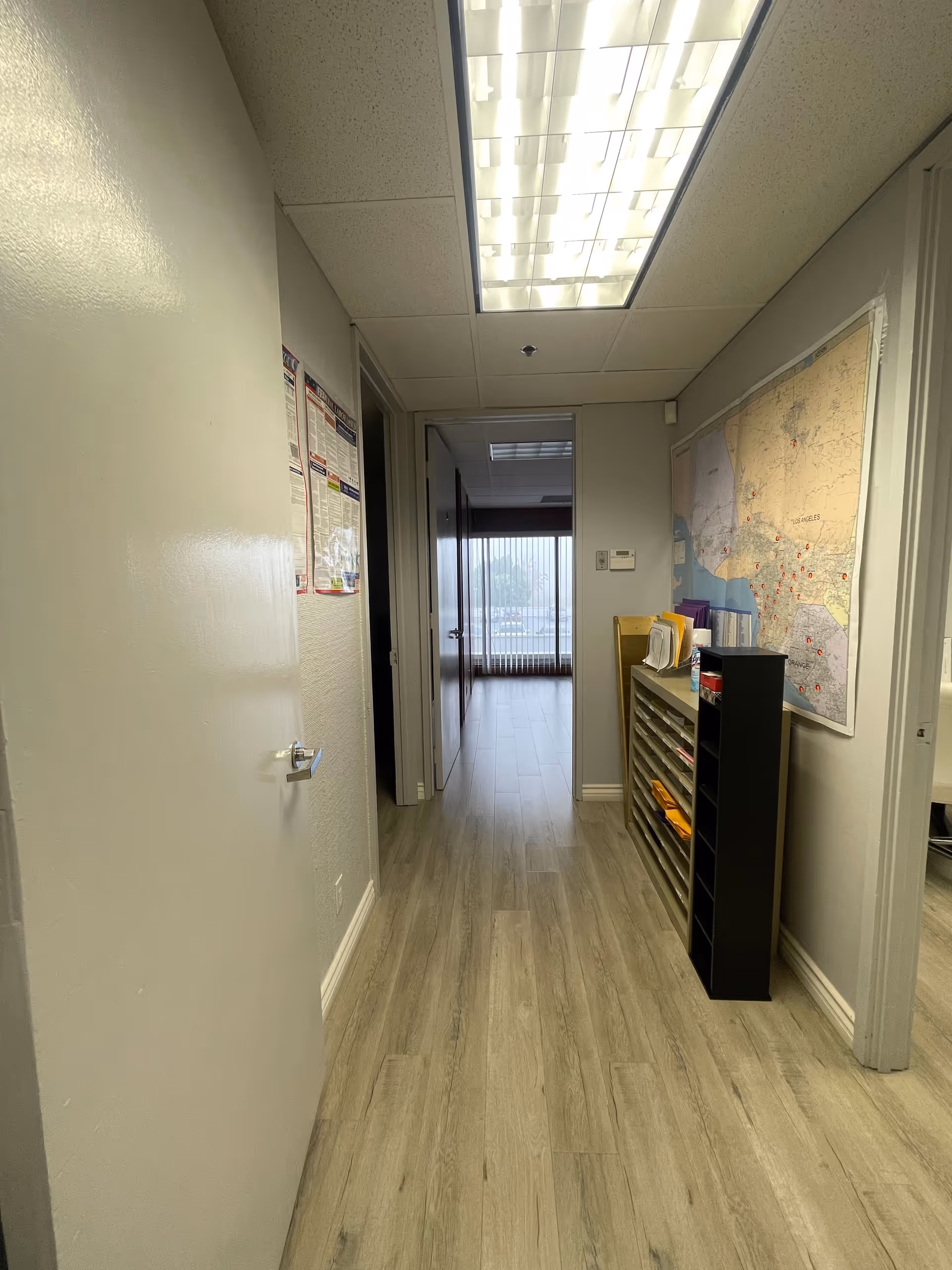 Narrow hallway inside SOCAL PREMIUM HEALTHCARE with wall map and shelf unit.