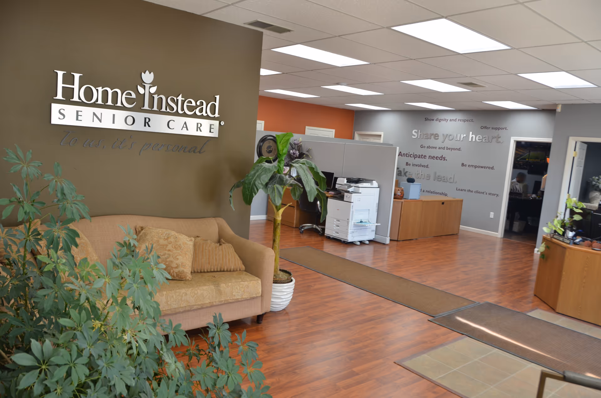 Lobby area of Home Instead Senior Care with a couch, plants, and reception desk.