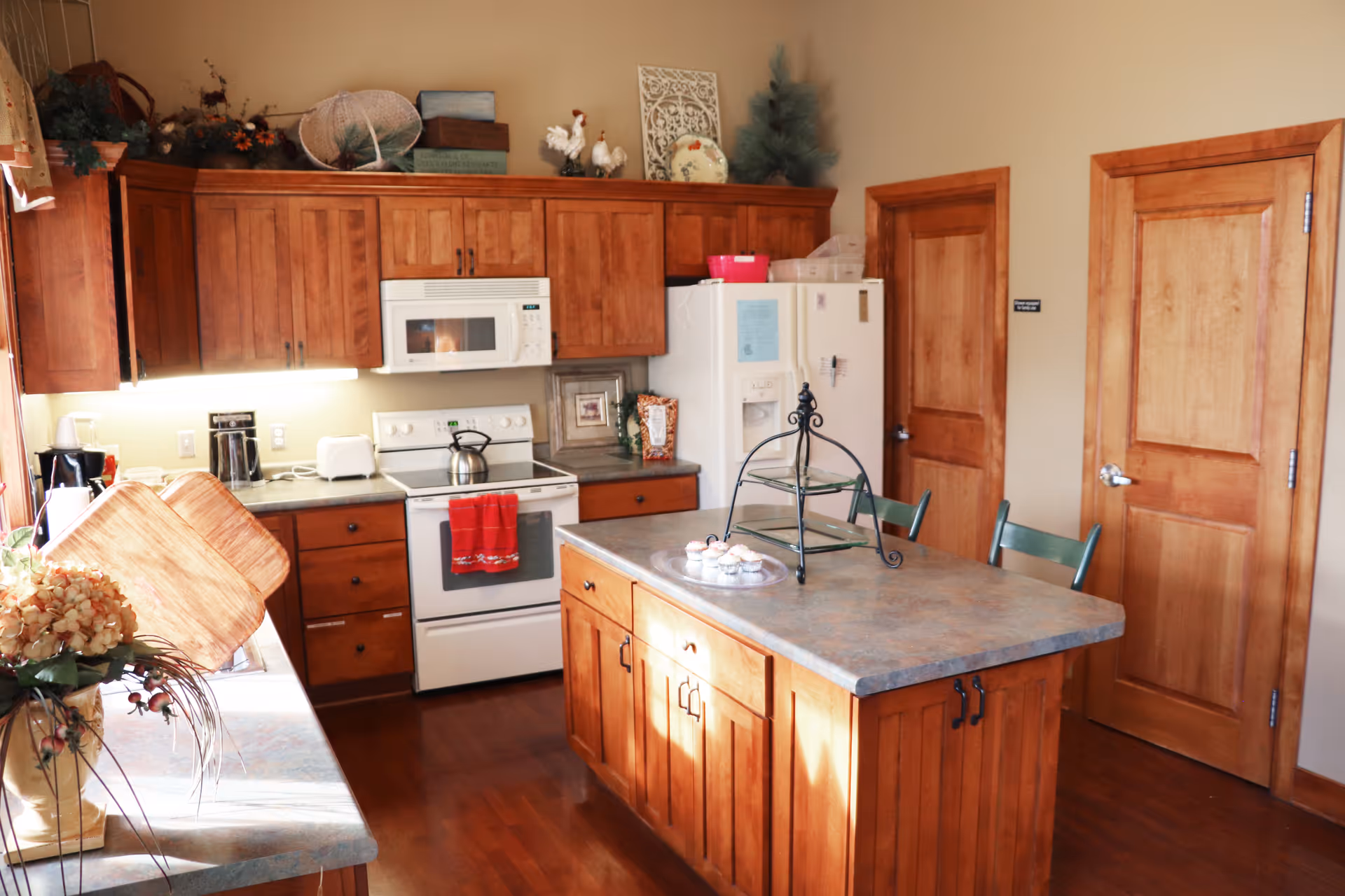 Bright kitchen in Hospice of Pella facility with wooden cabinets, island, and appliances.