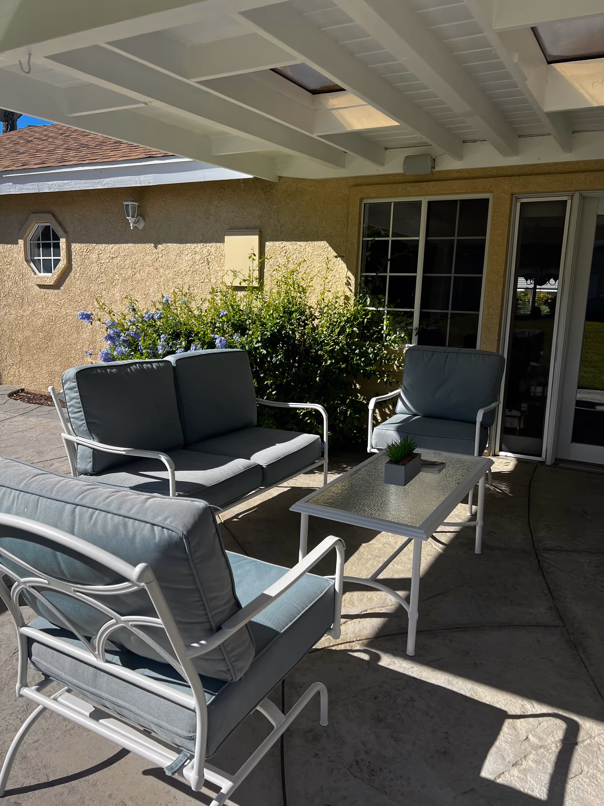 Outdoor patio with cushioned seating and a glass-topped table by sliding doors.
