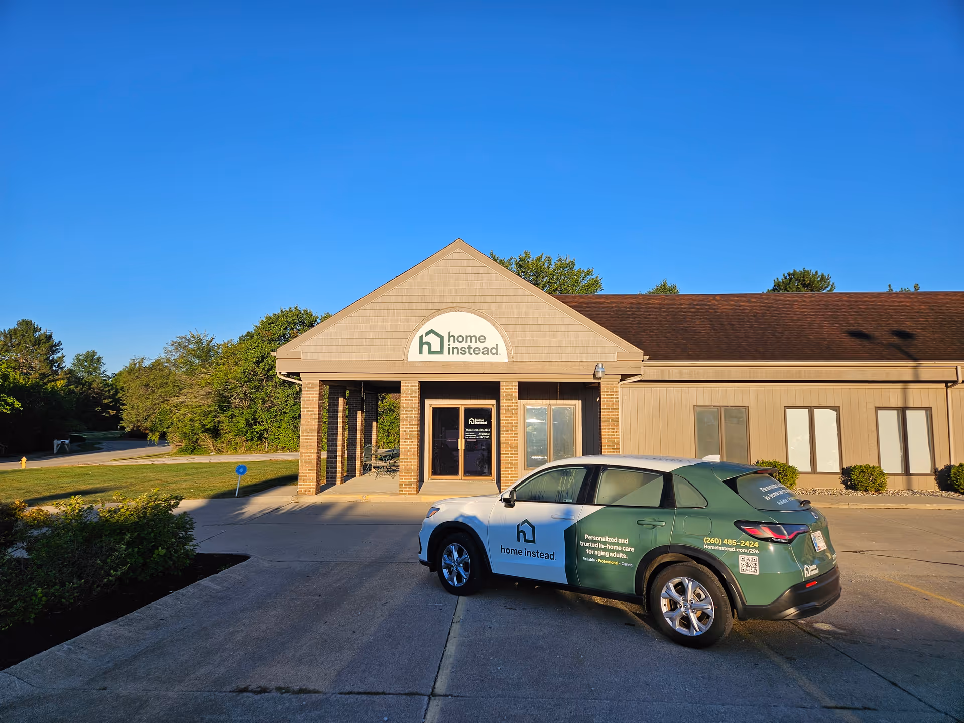 Exterior view of a Home Instead facility with a service car parked in front.