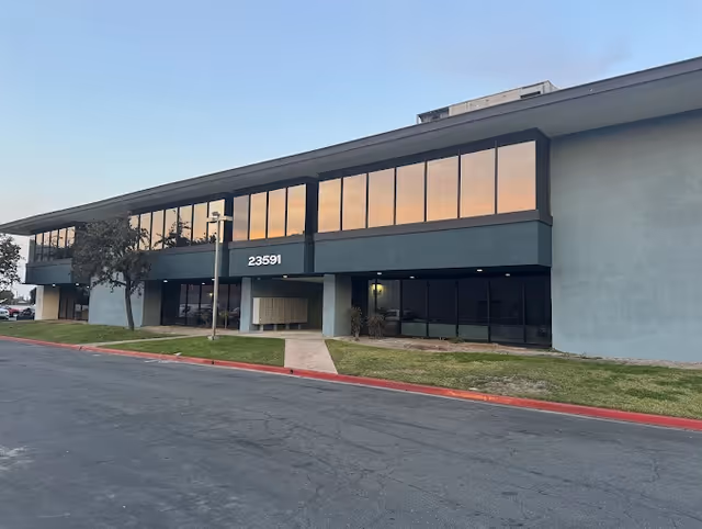 Exterior view of a modern two-story facility with large windows and a sidewalk entrance.