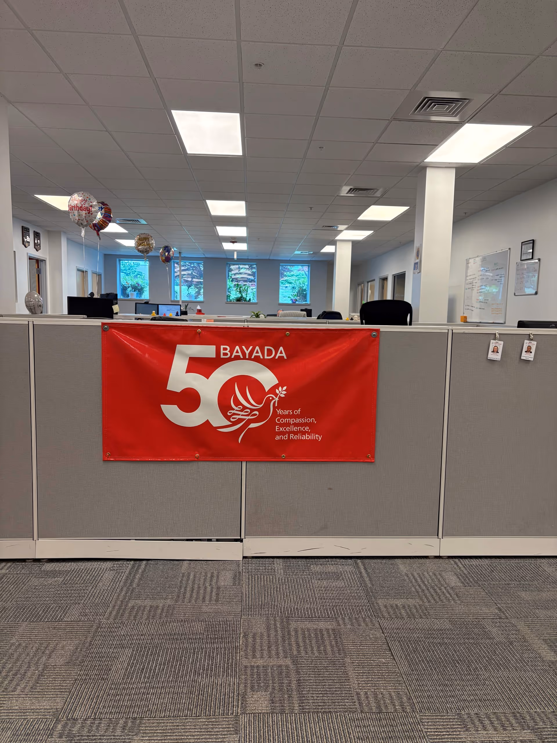 Office cubicles with a red BAYADA banner and balloons in the background.