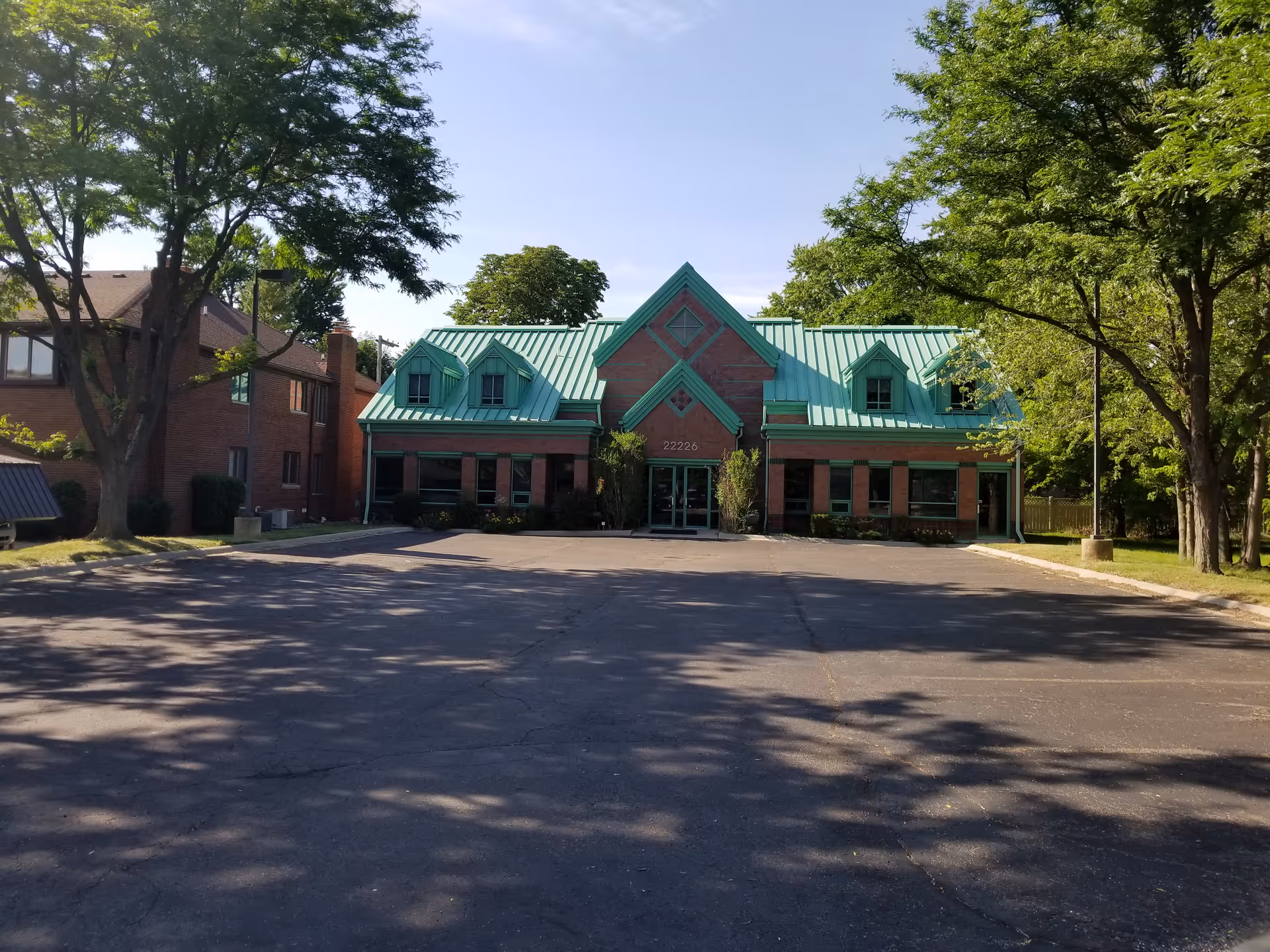 Exterior view of a senior living facility with a teal roof and parking lot.