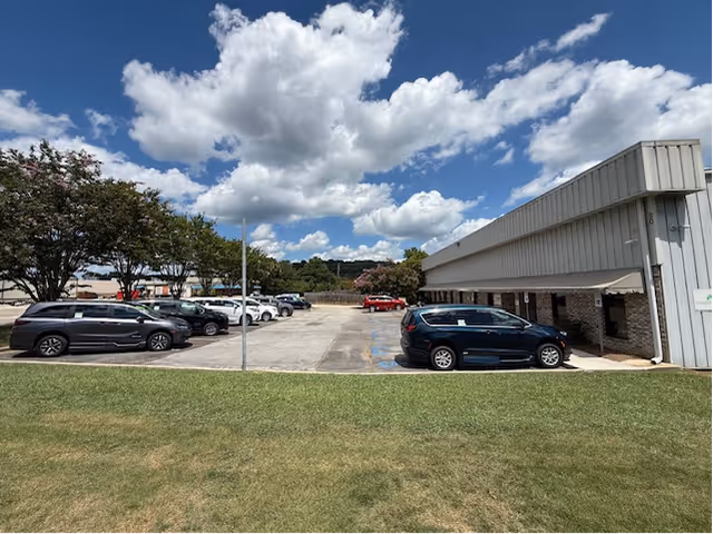 Exterior view of MobilityWorks facility with parked cars and blue sky