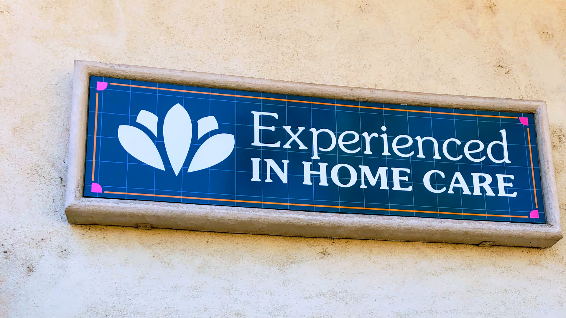 Blue sign on a stucco wall reads 'Experienced In Home Care' with a white logo.