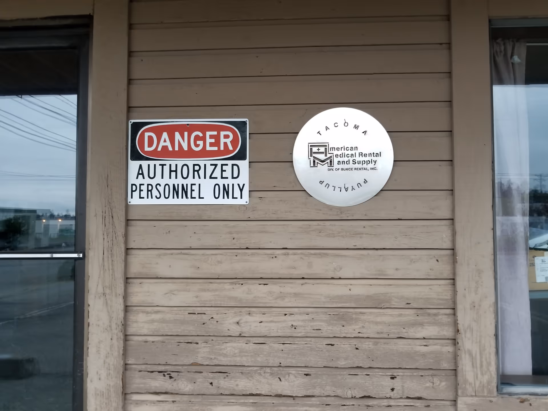 Wood exterior wall displays danger sign and circular medical rental sign.