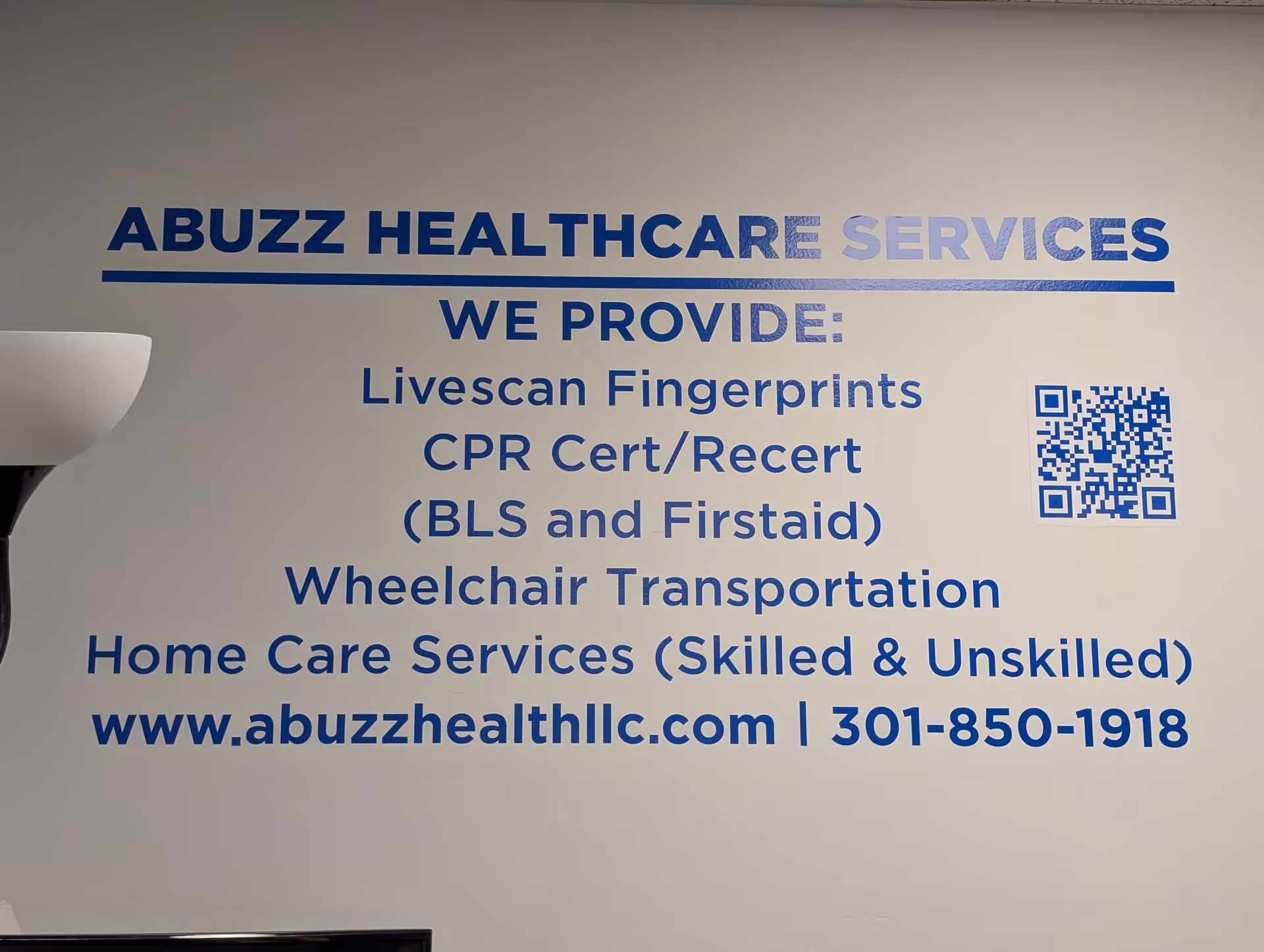 Interior wall with blue signage detailing Abuzz Healthcare Services offerings.