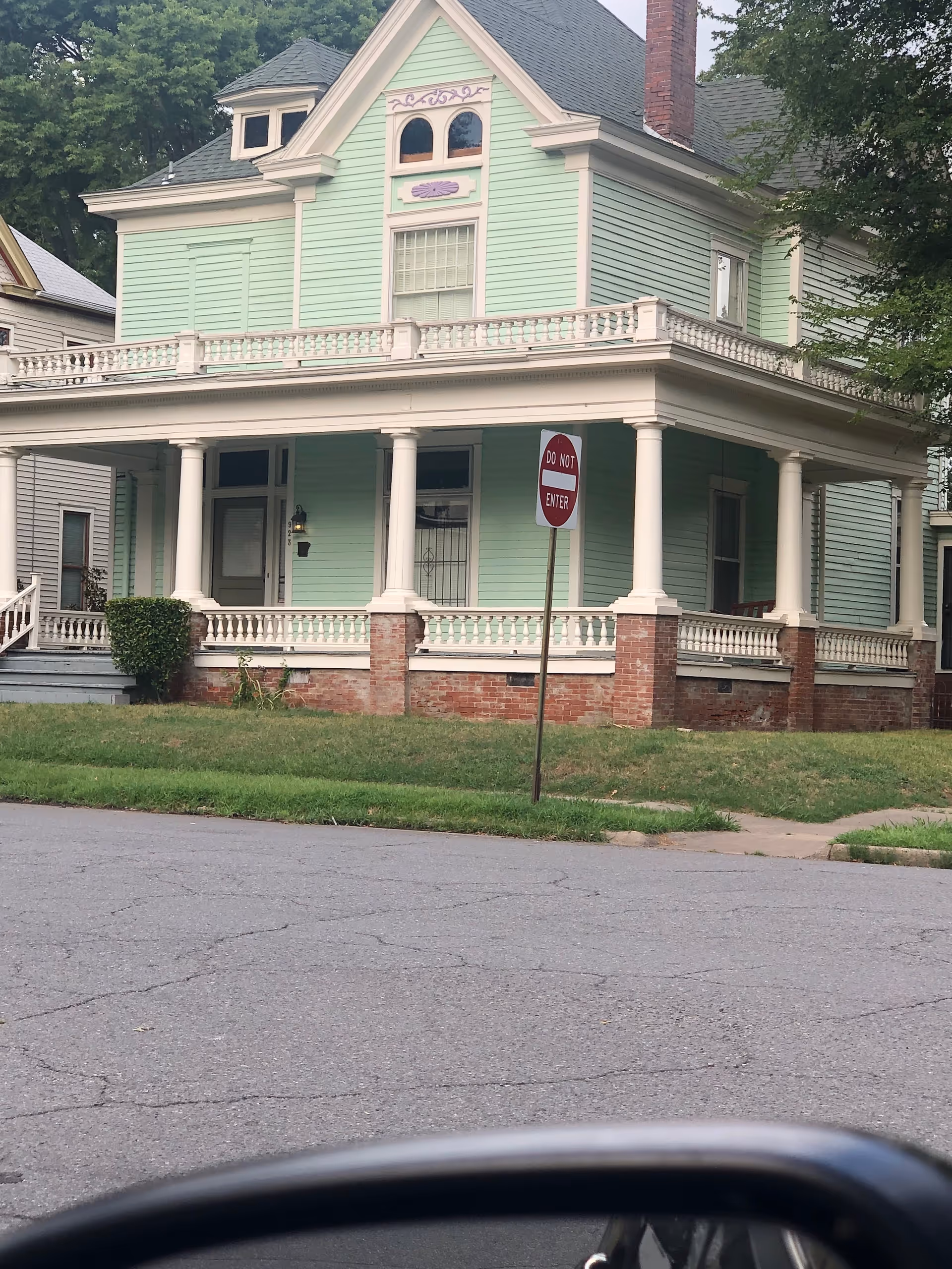 Pastel mint green, two-story building with wraparound porch and white columns.