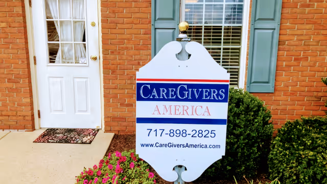CareGivers America sign in front of a brick building with shrubs and flowers