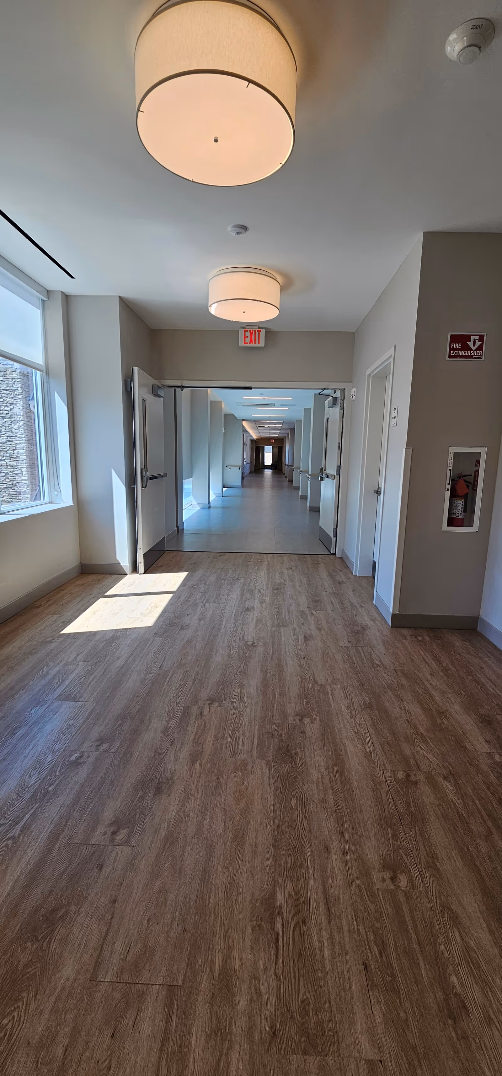Interior hallway of a senior living facility with open doors and windows.