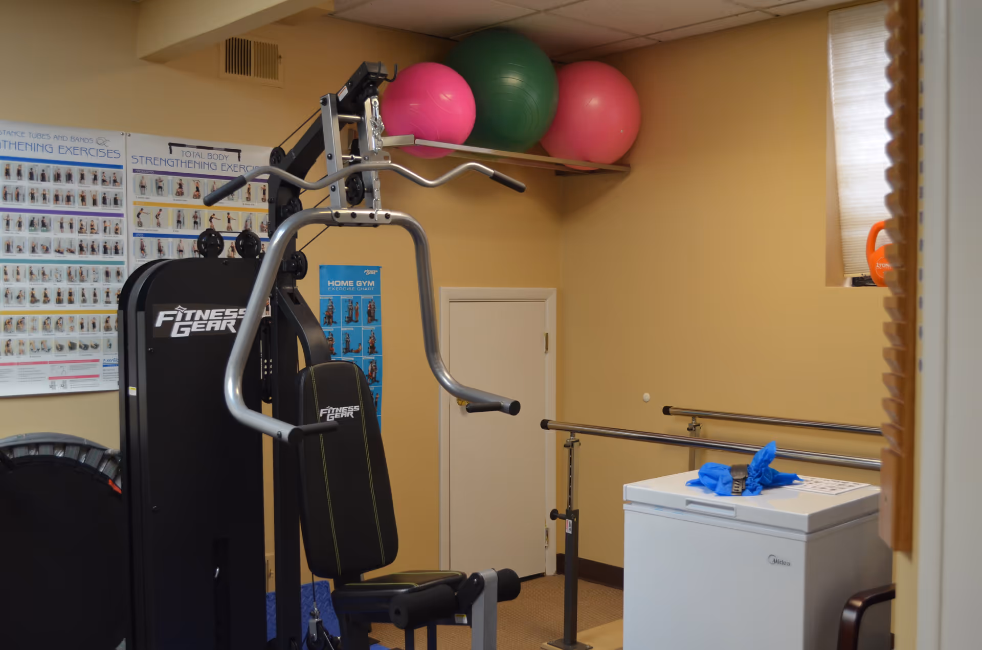 Interior gym in a senior living facility with exercise equipment and posters.