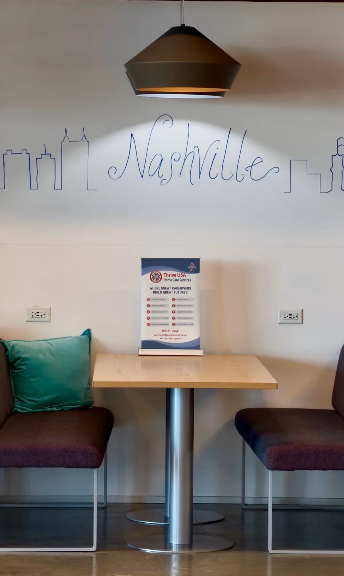 Interior seating area with a table, two chairs, and Nashville skyline wall art.