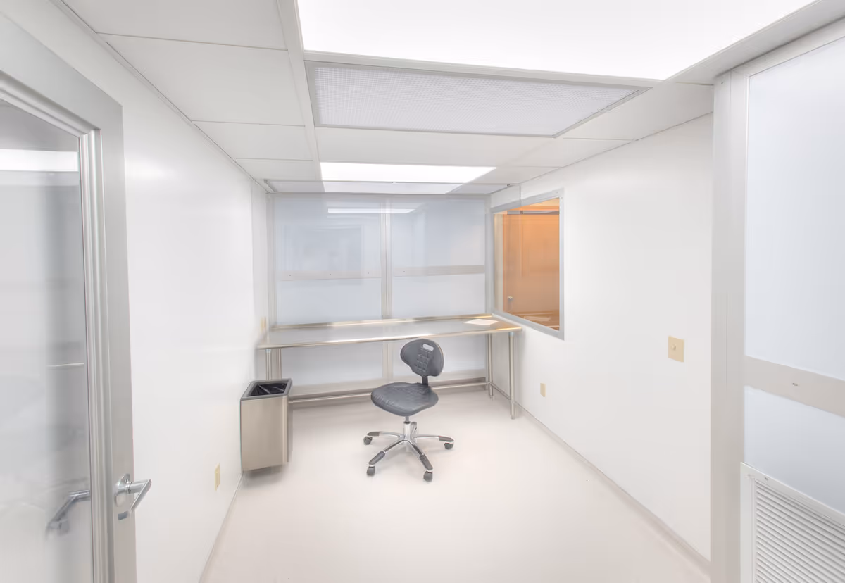 A small, empty medical office with a desk, chair, and frosted windows.