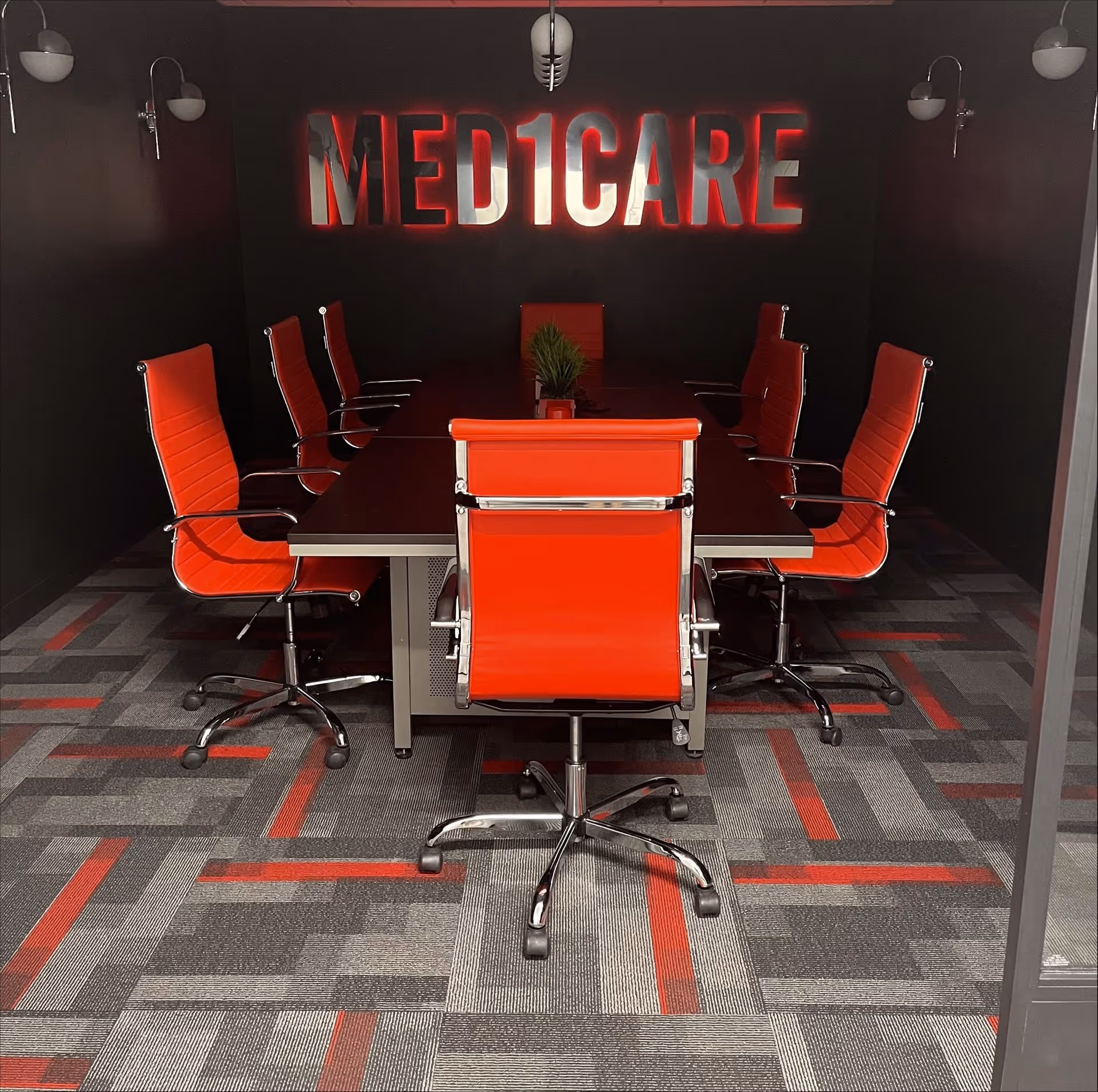 Red modern conference room with a long table and eight red chairs under Med1Care sign