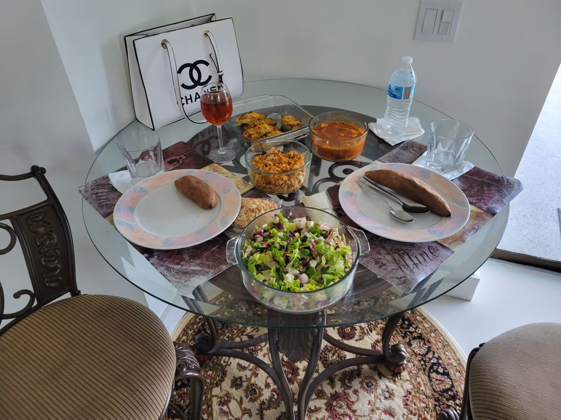 Round glass dining table set for a meal with salad and bread.