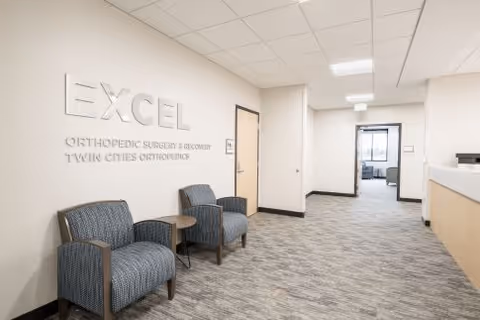 Hallway seating area in a medical facility with blue chairs and a reception desk.