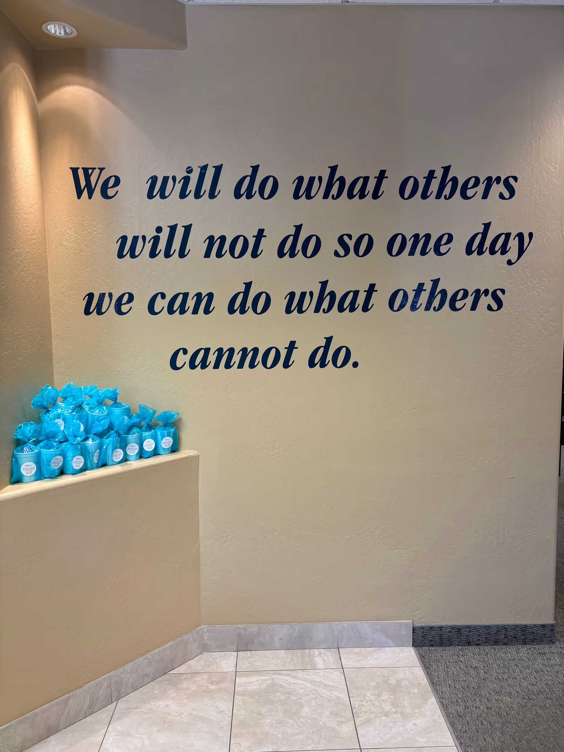 Interior wall with a large blue quote and teal wrapped items on a ledge.