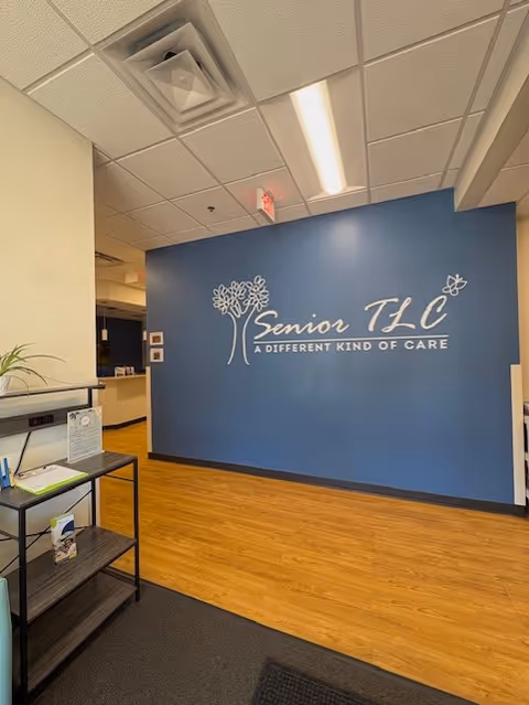 Blue wall featuring Senior TLC logo and slogan in a reception-style lobby