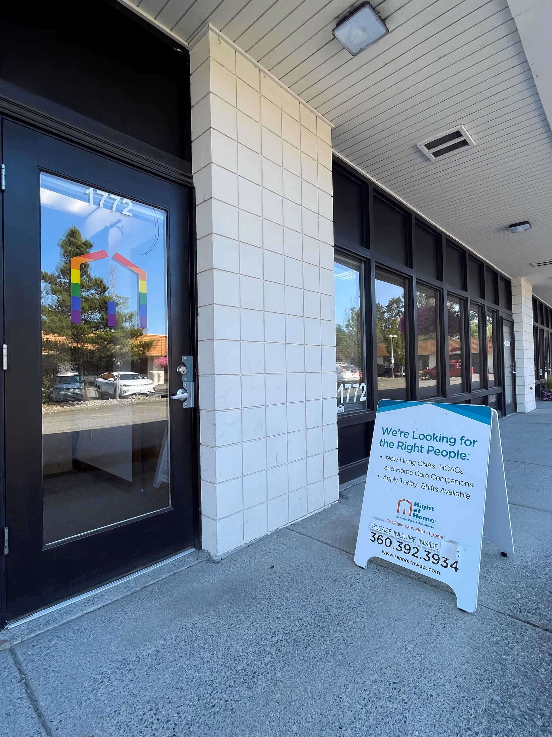 Exterior view of Right at Home building with glass doors and sidewalk sign.