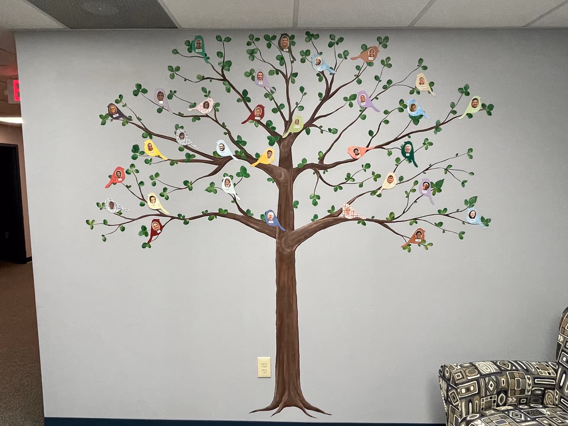 Indoor wall mural featuring a large tree with photo portraits on leaves.