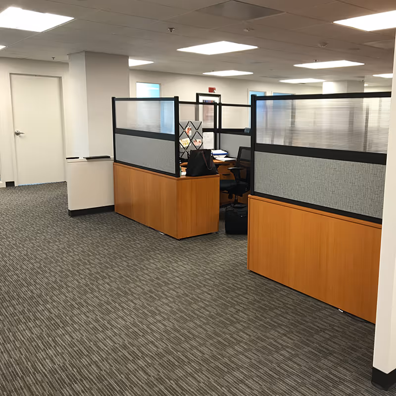 TheKey facility interior showing cubicles, a desk, and office chairs in an open corridor.