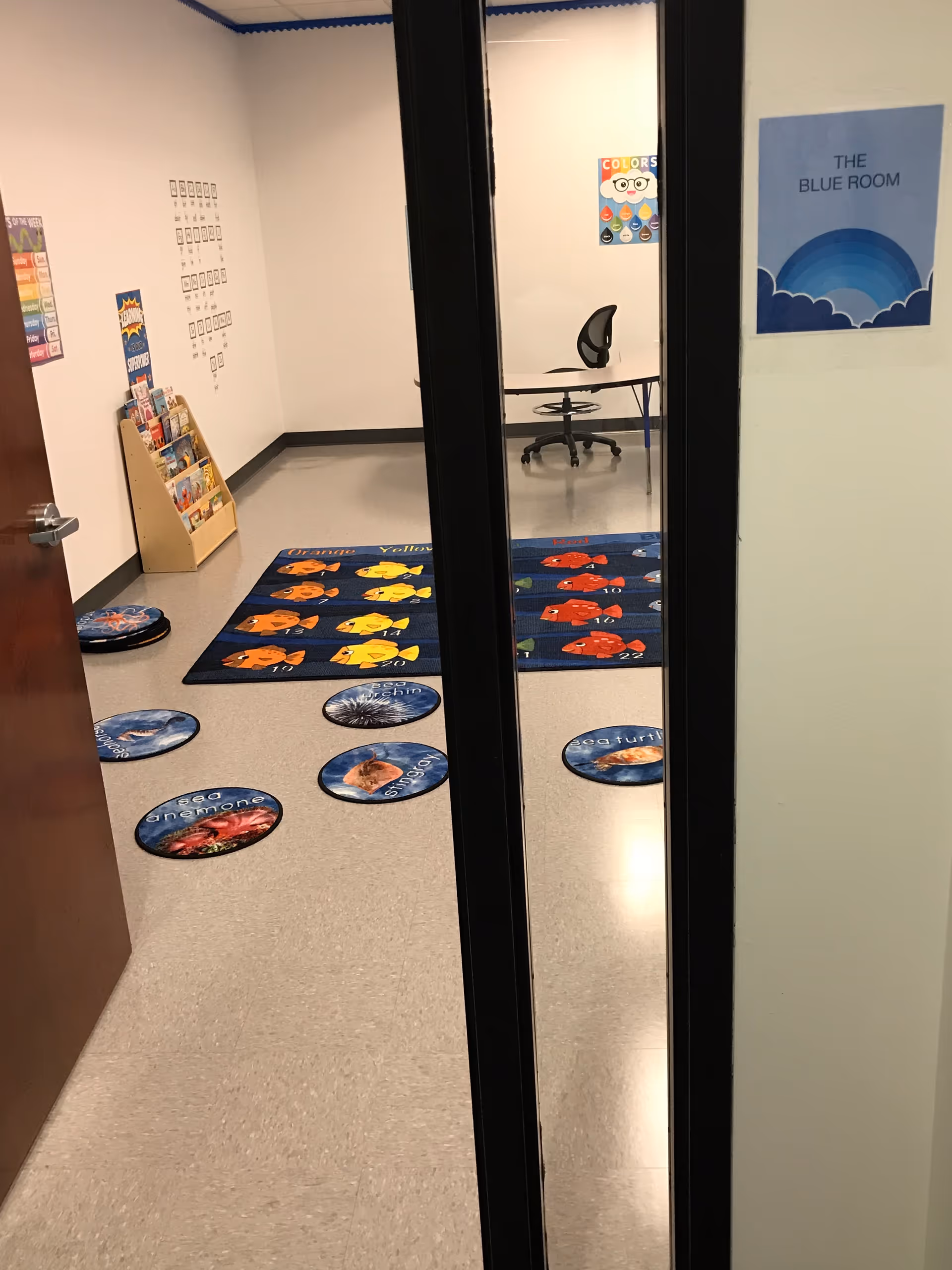 Interior hallway with colorful circular rugs and a small room containing a chair and table.