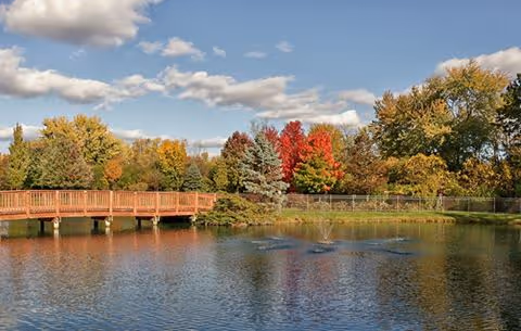 Scenic lakeside park with a wooden boardwalk, autumn trees, and calm water.