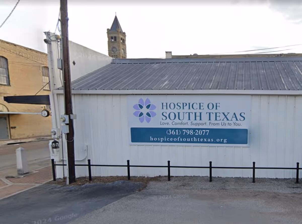 Exterior view of a white Hospice of South Texas building with a blue sign.