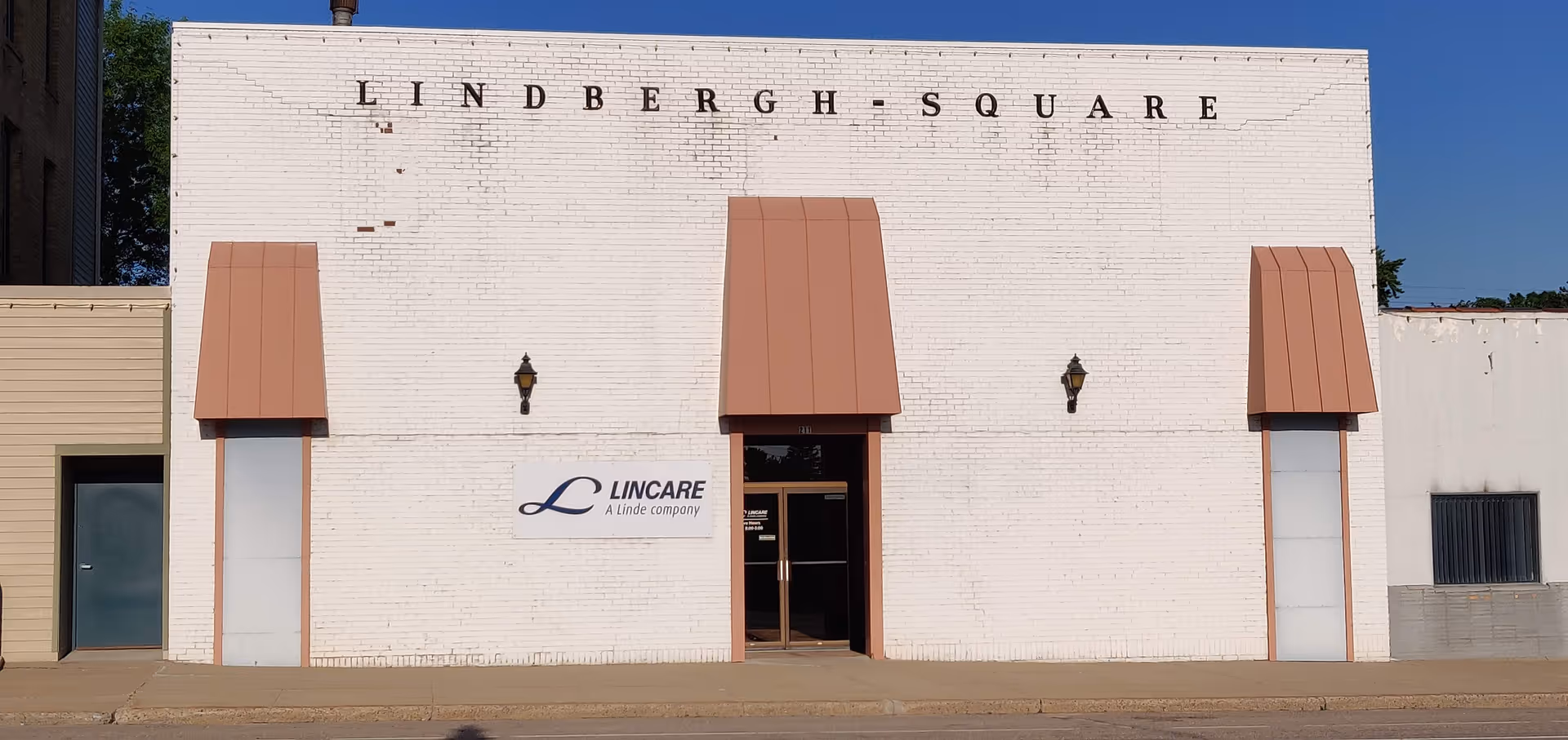 White brick building with LINCARE sign, brown canopies, and entrance.